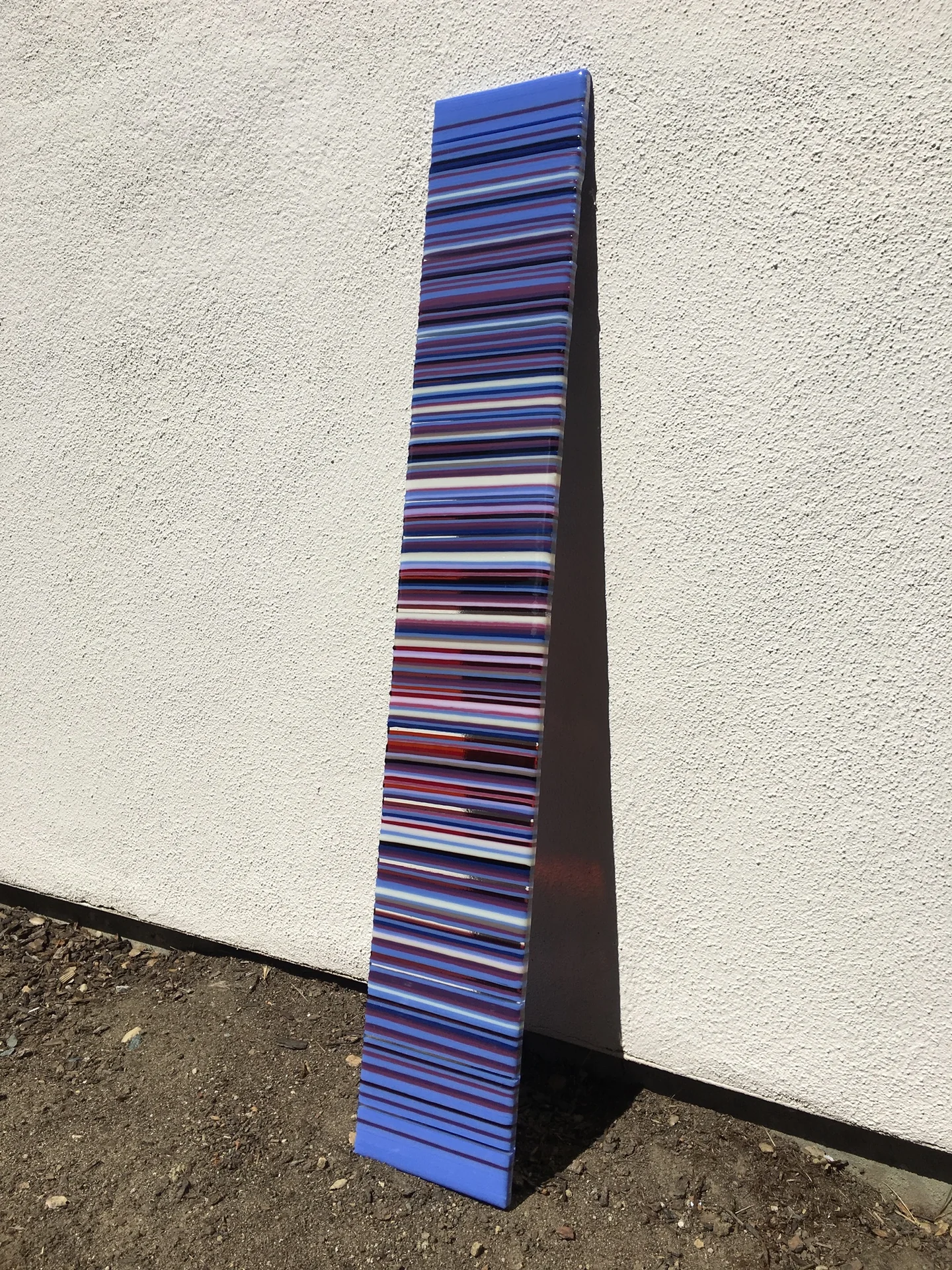 Tall purple and blue striped panel photographed beside a pale wall