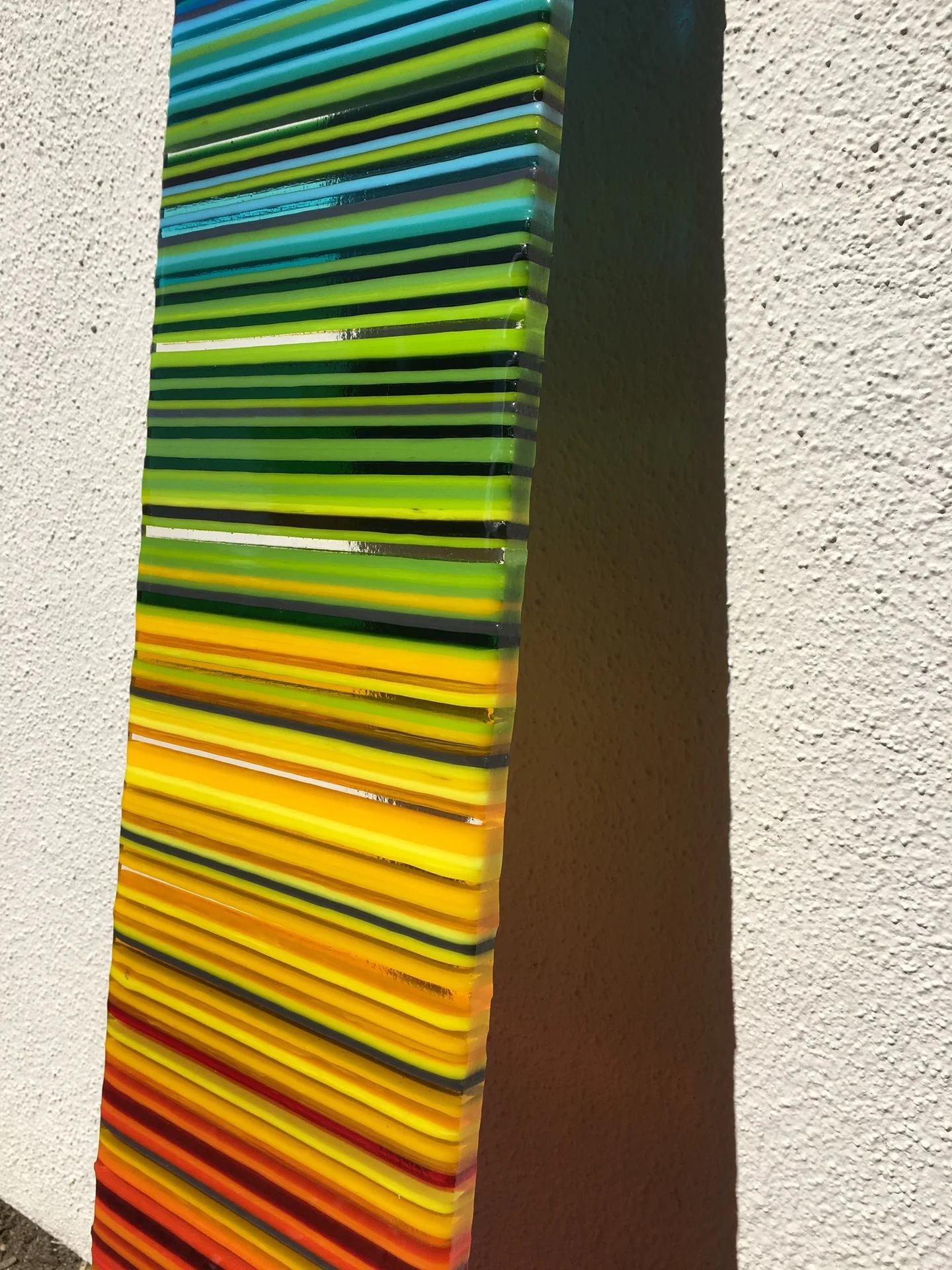 A close angled view of an upright striped panel moves from green bands through yellow to orange beside a dark edge.