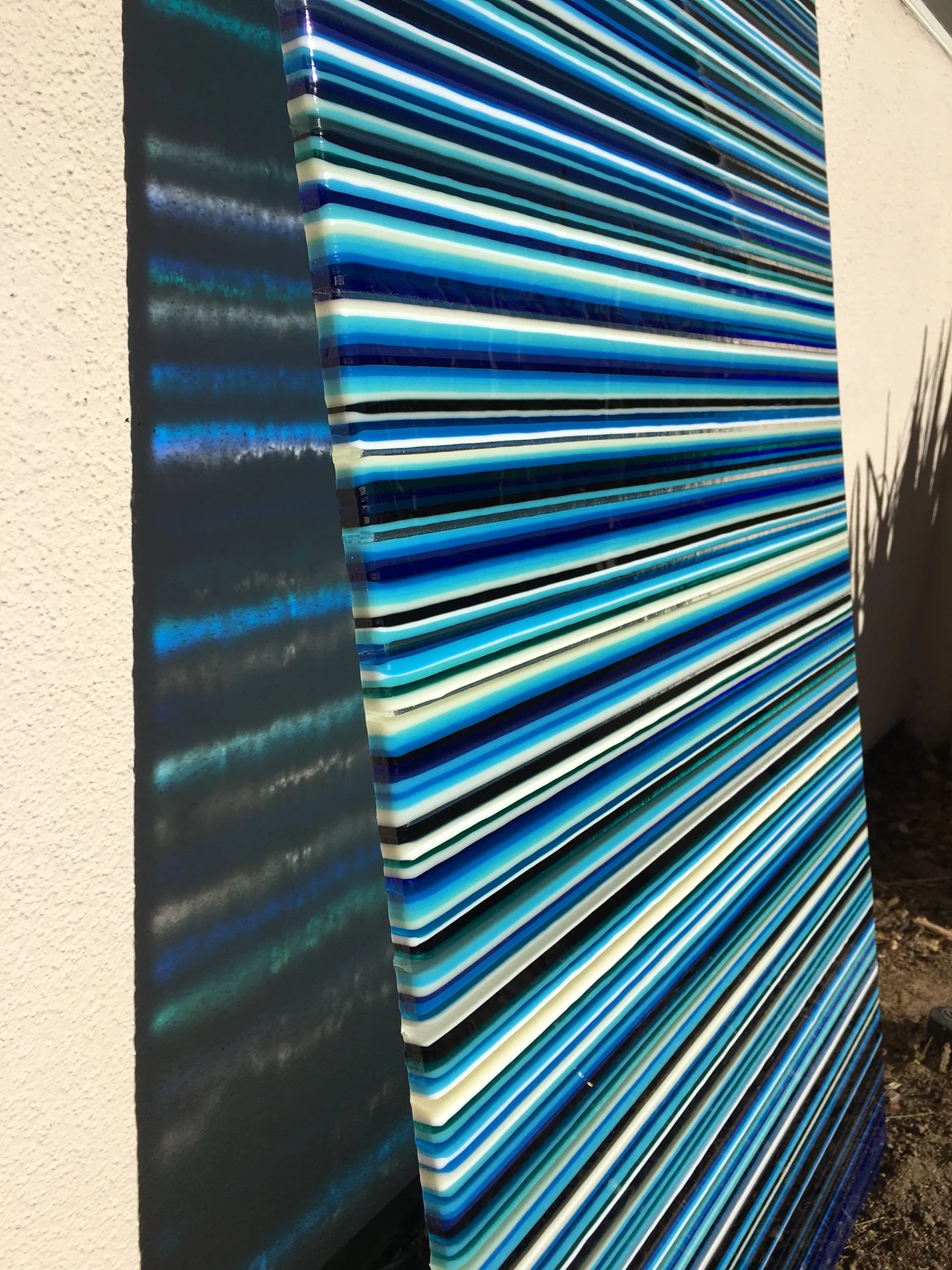 A close angled view shows dense blue, turquoise and white horizontal stripes beside a dark vertical edge.