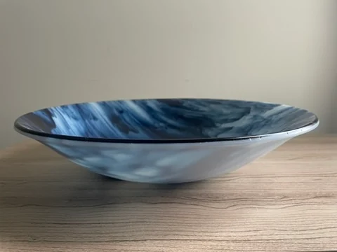Blue-and-white patterned shallow bowl seen from the side on a wooden tabletop