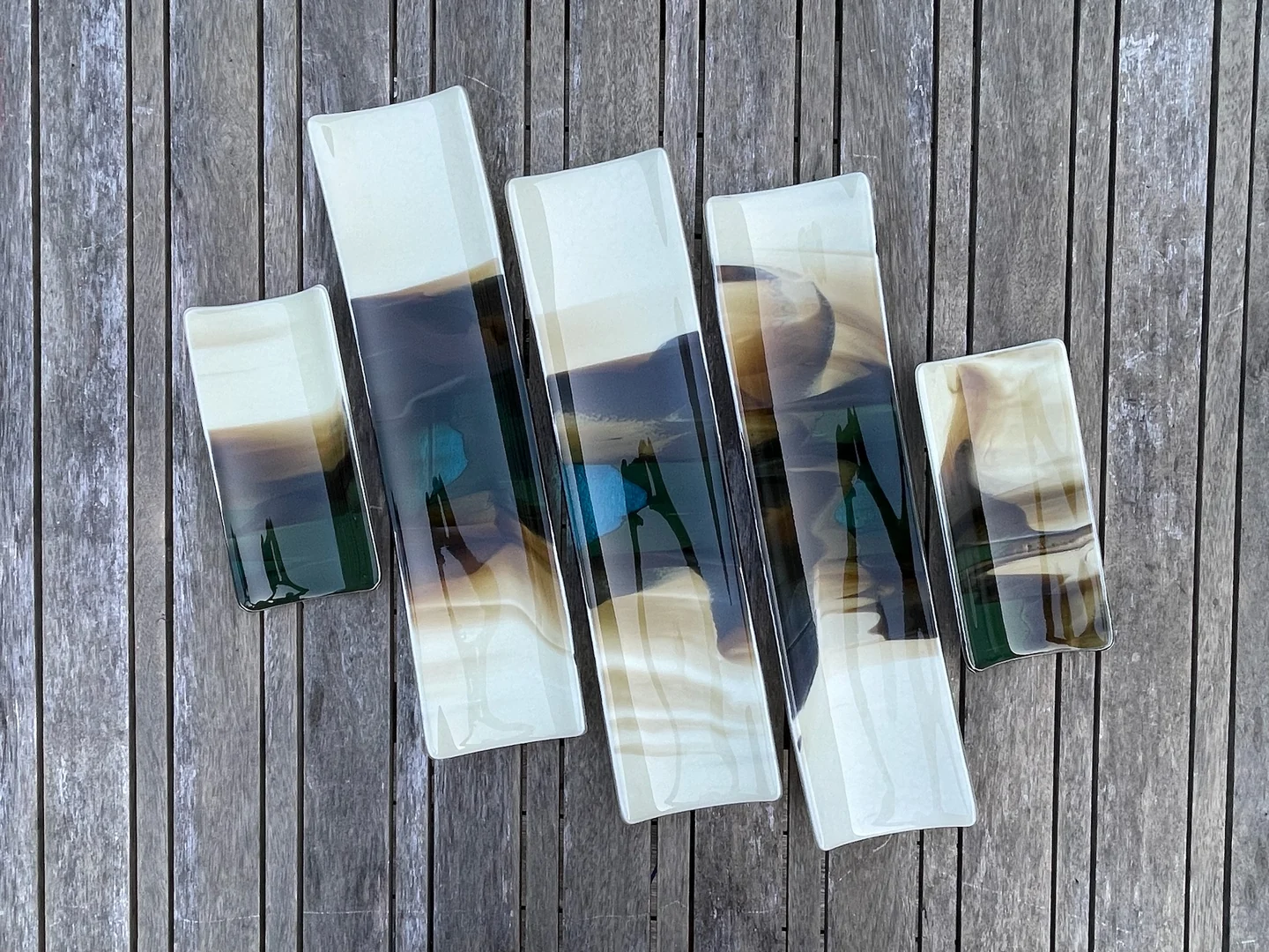 Five long narrow forms with pale ends and blue-gray centers overlap slightly on weathered boards.