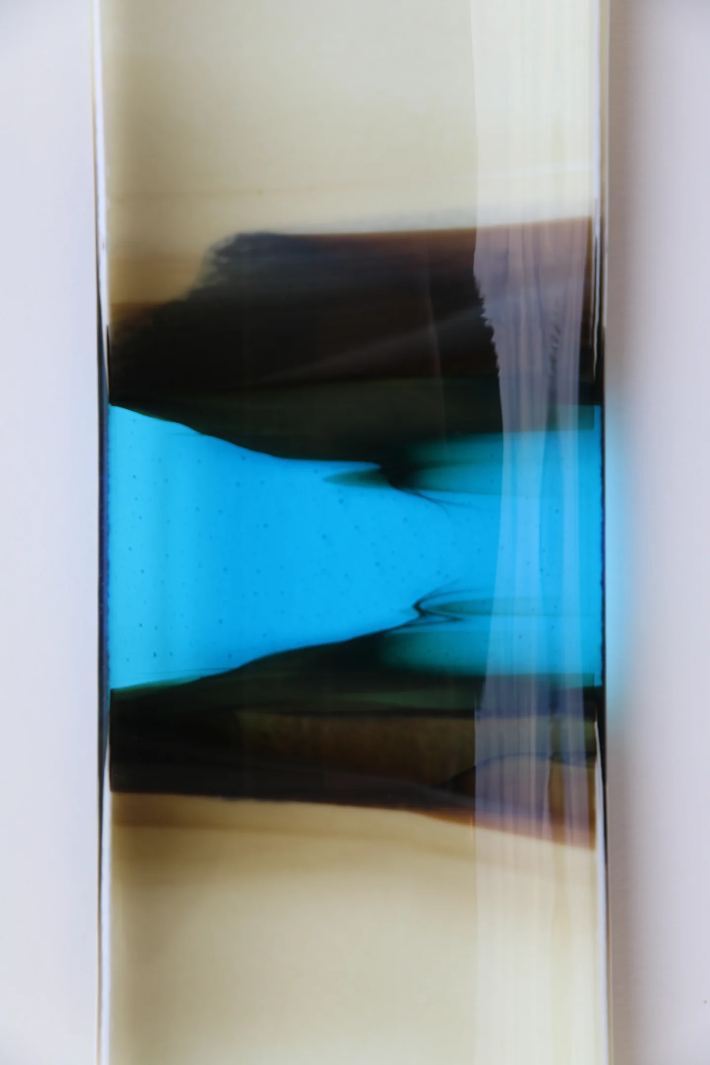A close view of a tall pale-edged form shows a vivid blue band between irregular near-black horizontal areas.