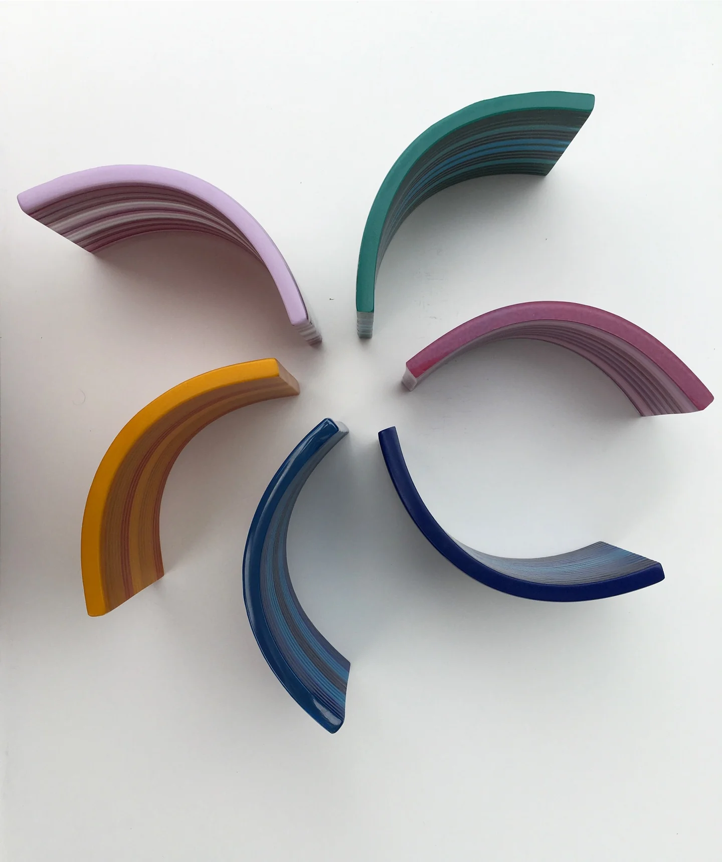 Six small curved striped forms in pink, green, amber and blue are spaced around an open center on white.