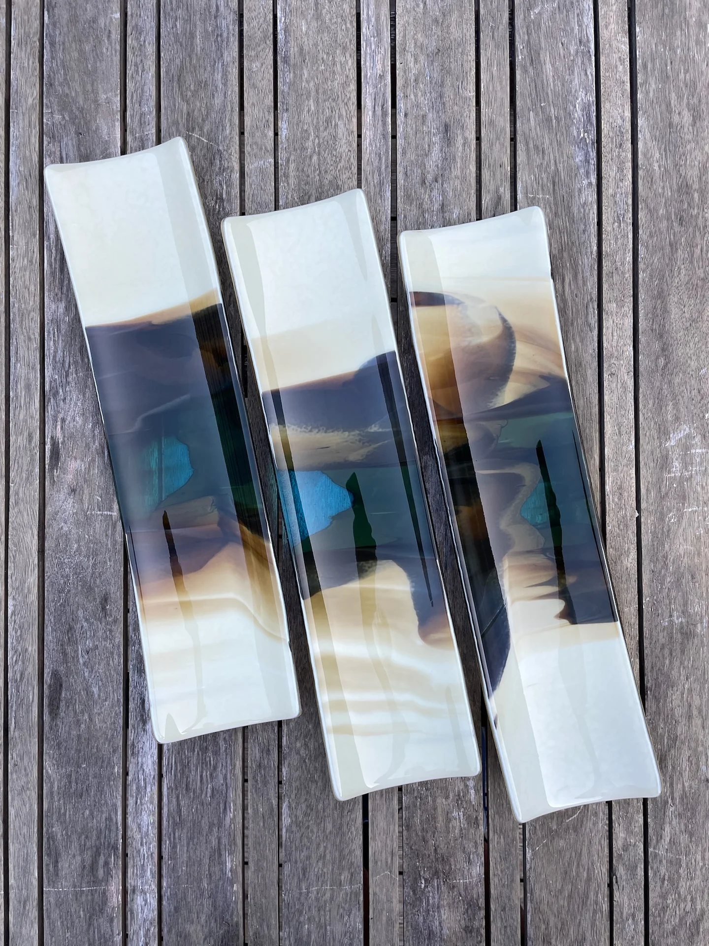 Three long narrow forms with pale ends and dark blue-gray centers lie close together on weathered boards.