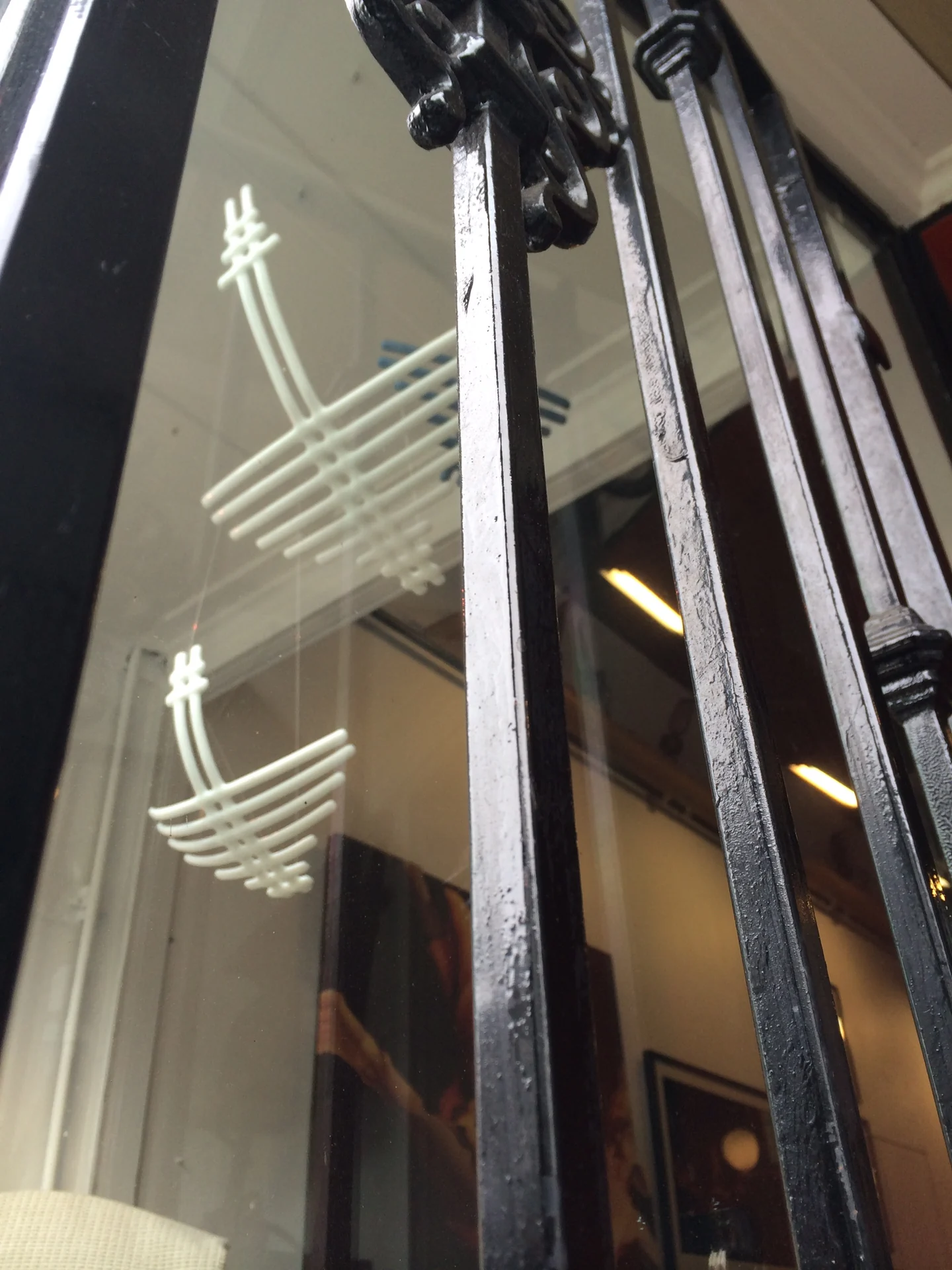 A close view through reflective glazing shows white curved horizontal lines crossing vertical lines beside dark framing.